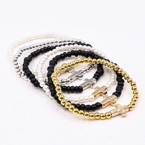 Detail of a six-piece elastic beaded bracelet set featuring crosses and faux pearls