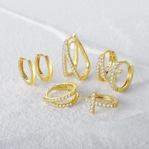 Macro shot of S925 sterling silver gold plated hoop earrings with cross and zircon details