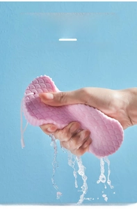 Pink exfoliating bath sponge with fish scale texture and hanging rope being squeezed