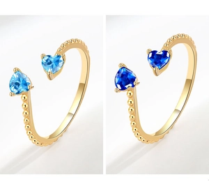 Macro detail of gold-plated open rings featuring twin heart-cut blue gemstones