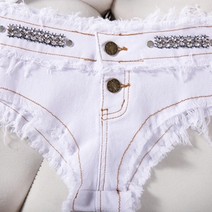 Dettaglio di pantaloncini in denim bianco con strass brillanti e bordi sfrangiati