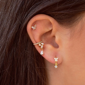 Close-up of gold butterfly earrings with zircon studs and ear cuff styling on model