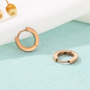 Close-up of rose gold minimalist round hoop earrings on soft fabric with dried flower