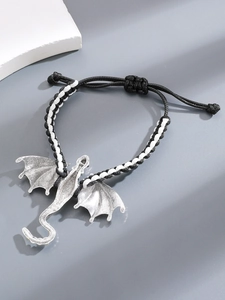 Detail van een vintage zilveren drakenbedel op een zwart-wit gevlochten armband voor unisex