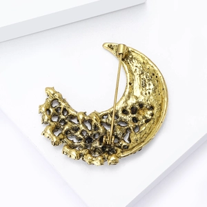 Macro detail of crescent moon brooch with vintage texture and inlaid small dark stones