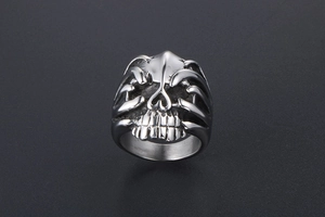 Macro shot of silver punk skull ring featuring two skeletal hands covering the eye sockets