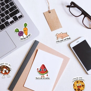 Close-up of cute cartoon waterproof stickers applied to a laptop and various stationery items