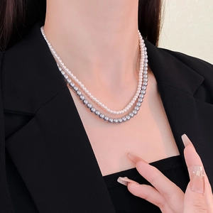Close-up of double layer necklace featuring fine white pearls and bold gray pearls
