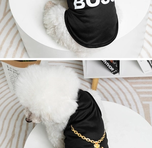 Detail of a black pet vest with BOSS print and gold chain pattern on a white dog