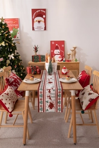Close-up of festive Christmas table runner and reindeer pillows in a warm holiday setting