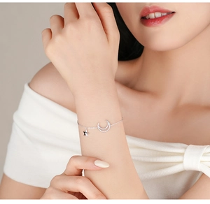 Detailed view of silver star and moon charms on a delicate bracelet worn on wrist