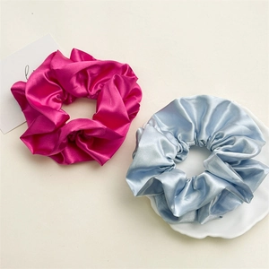Detail of rose pink and light blue pleated satin scrunchies with glossy silk texture