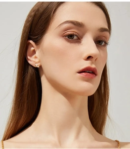 Close-up of star-shaped gold earrings with small diamonds worn by a female model