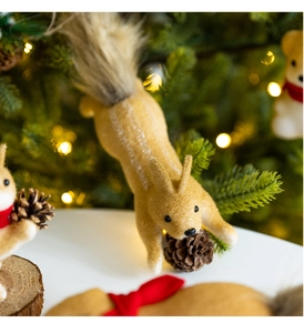 Close-up of a flocking squirrel ornament holding a natural pinecone on a Christmas tree