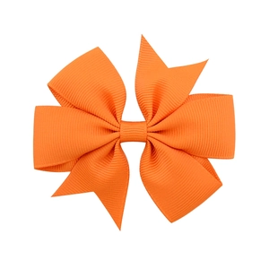 Detail showing the textured bright orange grosgrain ribbon bow with multi-layer stitching