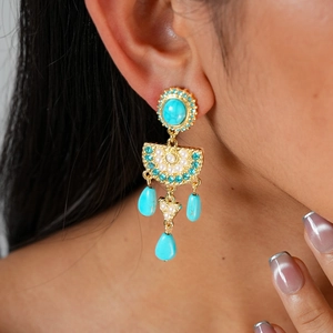 Macro detail of ethnic drop earrings with turquoise, pearls, and crystals on a model