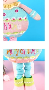 Detail of knitted Christmas doll wearing a light blue dress with Merry Christmas embroidery