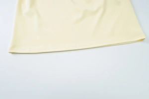 Close-up of the fine sewing craftsmanship on the pale yellow mesh dress hemline