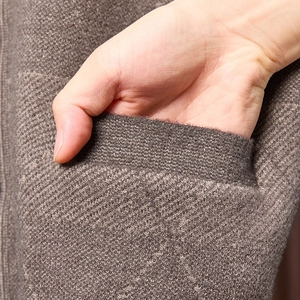 Makroaufnahme einer tiefbraunen Strickjacke mit einem funktionalen Seitentaschendetail