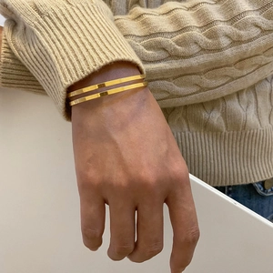 Minimalist 18k gold plated stainless steel double line open bangle worn by a model