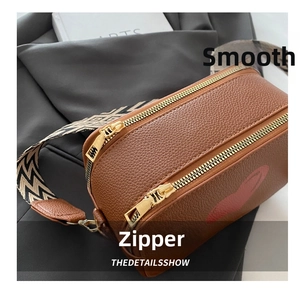 Detail of dual metal zippers on brown lychee leather bag with geometric strap