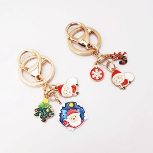 Detailed close-up of Santa Claus and Christmas tree enamel pendants on gold keychains