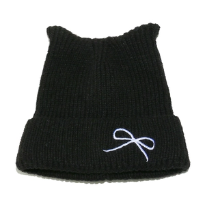 Close-up of black knit beanie with cat ear shape and white bow embroidery detail
