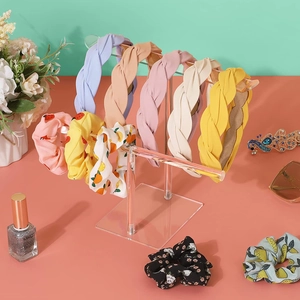 Detail of colorful woven headbands and floral hair ties on a clear acrylic display stand
