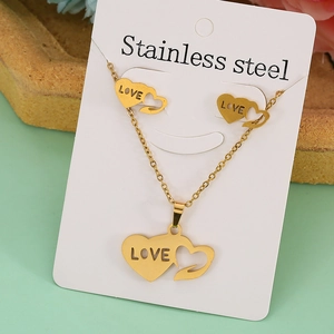 Close-up of gold stainless steel jewelry set with heart charms engraved with LOVE