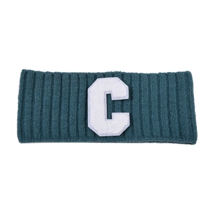 Détail du bandeau en maille vert foncé avec broderie vintage de la lettre C