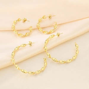 Detailed view of two pairs of twisted gold hoop earrings on soft silk background