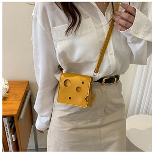 Close-up of yellow cheese-shaped mini crossbody bag with unique round cutout details