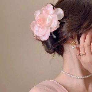 Detail of pink fabric flower hair clip styled on elegant updo with pearl jewelry