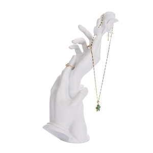 White resin hand-shaped jewelry display stand showing gold rings and necklaces