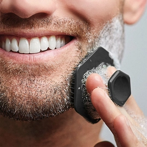 Close-up of hexagonal black silicone beard brush with shaving foam for deep facial cleaning