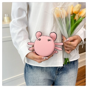 Pink leather crab-shaped coin purse with metal ring detail held by a model with tulips