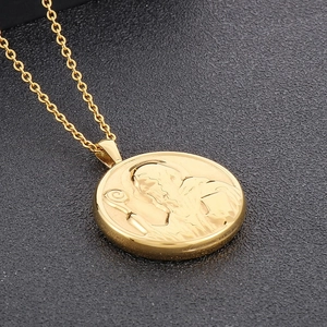 Gros plan d'un pendentif médaille Saint-Benoît doré sur un fond noir texturé