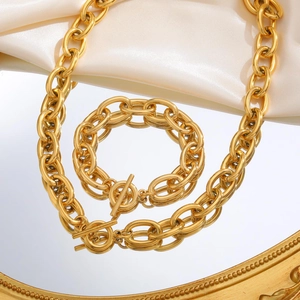 Gold chunky chain necklace and bracelet set with OT clasp on mirror surface