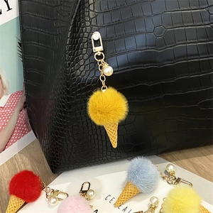 Close-up detail of a cute plush ice cream keychain with a pearl charm on a bag