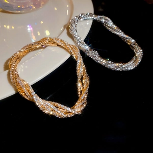 Macro shot of twisted multi-layer bracelets in gold and silver finish with crystal pavé