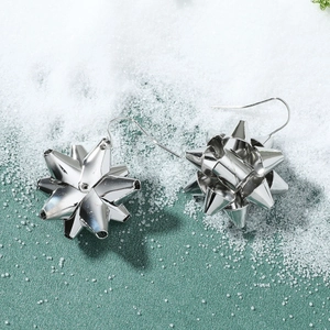 Detail of silver alloy star-shaped bow earrings with festive metallic finish texture