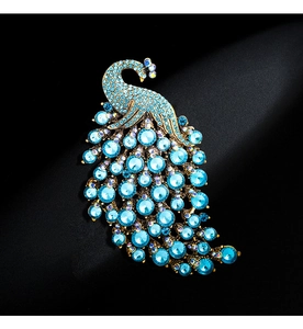 Macro shot of colorful peacock brooch with blue rhinestones and gold-tone peacock feathers