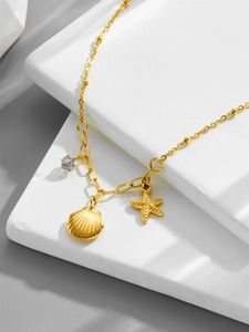 Detail of 18k gold starfish shell necklace with zircon pendant on white stone