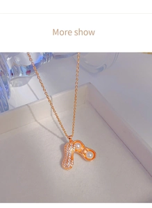 Macro d'un pendentif cacahuète en or rose avec perles et zircons dans un écrin blanc