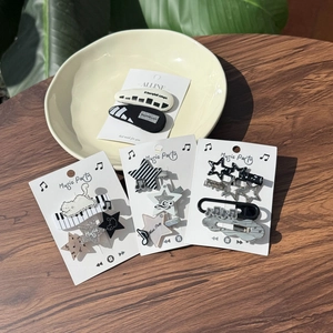 Detail of music themed hair clips featuring piano keys and cat motifs on a ceramic tray