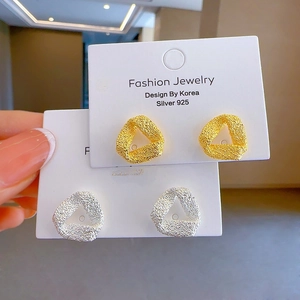 Close-up of matte geometric triangle stud earrings in gold and silver finish 925 silver