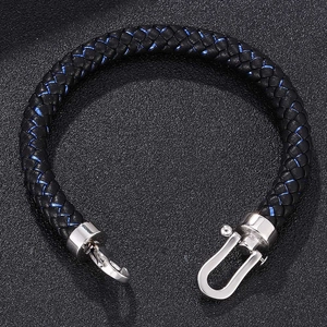 Detail of black braided leather bracelet with blue stitching and silver horseshoe clasp