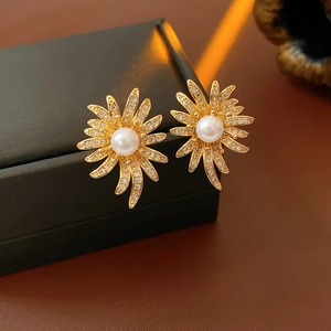 Macro shot of gold floral pearl earrings with micro-inlaid cubic zirconia on black box