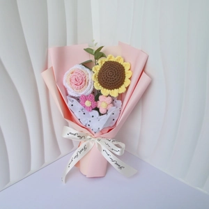 Close-up of handmade crochet sunflower and rose bouquet in pink wrapping with a ribbon