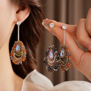 Detailed macro view of long teardrop tassel earrings with colorful crystals on a model